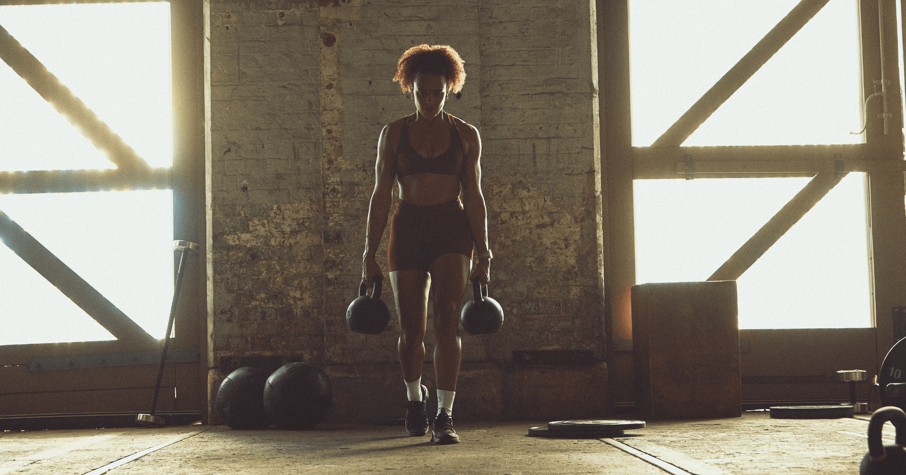Girl carrying two heavy kettlebells as she walks forward